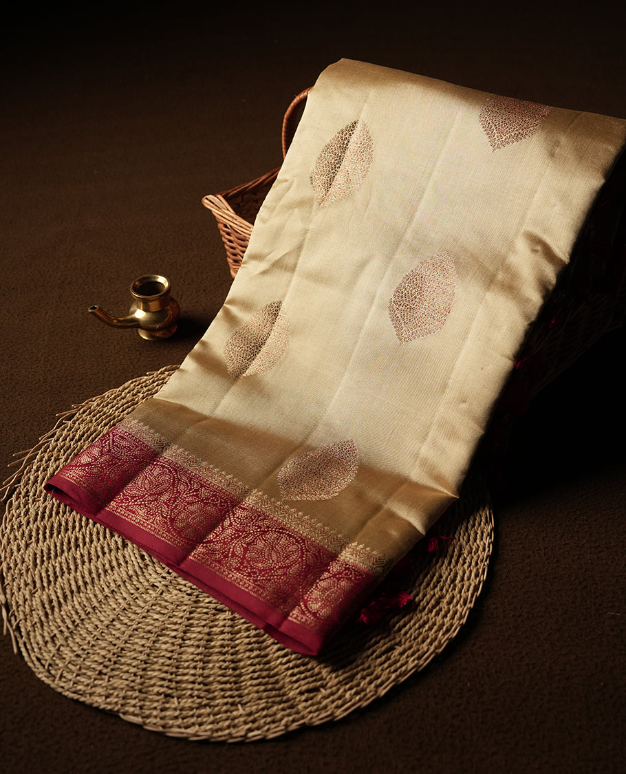 Cream Beige Colour Banaras Soft Silk Saree with Gold Zari Leaf Diamond Buttas, Intricate Multi-Layered Floral Border, Grand Pallu with Ornate Floral Brocade Motifs in Deep Red and Gold Tones, and Matching Red Blouse.