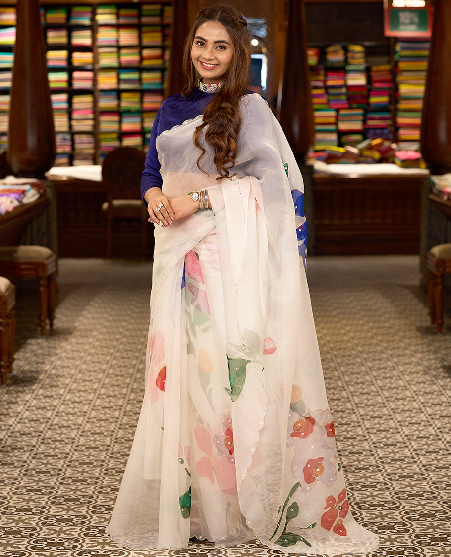 White colour pure organza silk saree featuring digitally printed fancy floral designs, adorned with delicate small mirror work, and finished with an elegant scalloped border, paired with a self colour crepe printed blouse