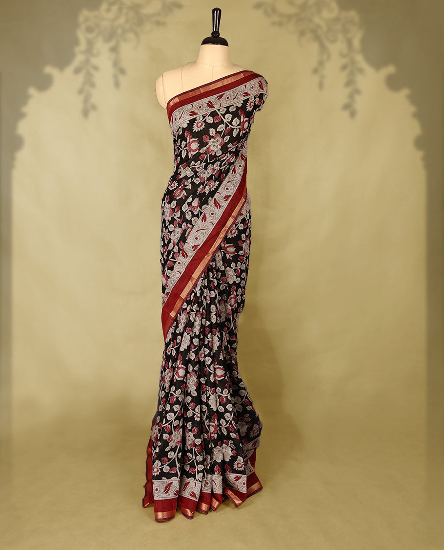 Black colour chanderi cotton saree with floral printed body, maroon border with traditional floral motifs, intricately designed pallu with peacock and floral patterns, with matching blouse