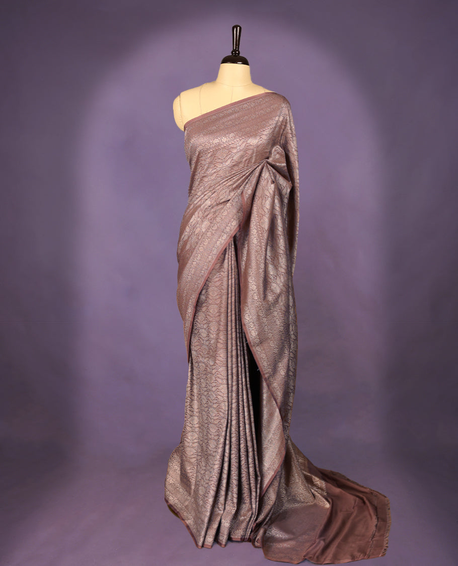 Pastel brown colour semi Banaras Katan saree featuring an antique silver zari jacquard body, complemented by a self colour traditional border with a floral kodi design, paired with a matching blouse