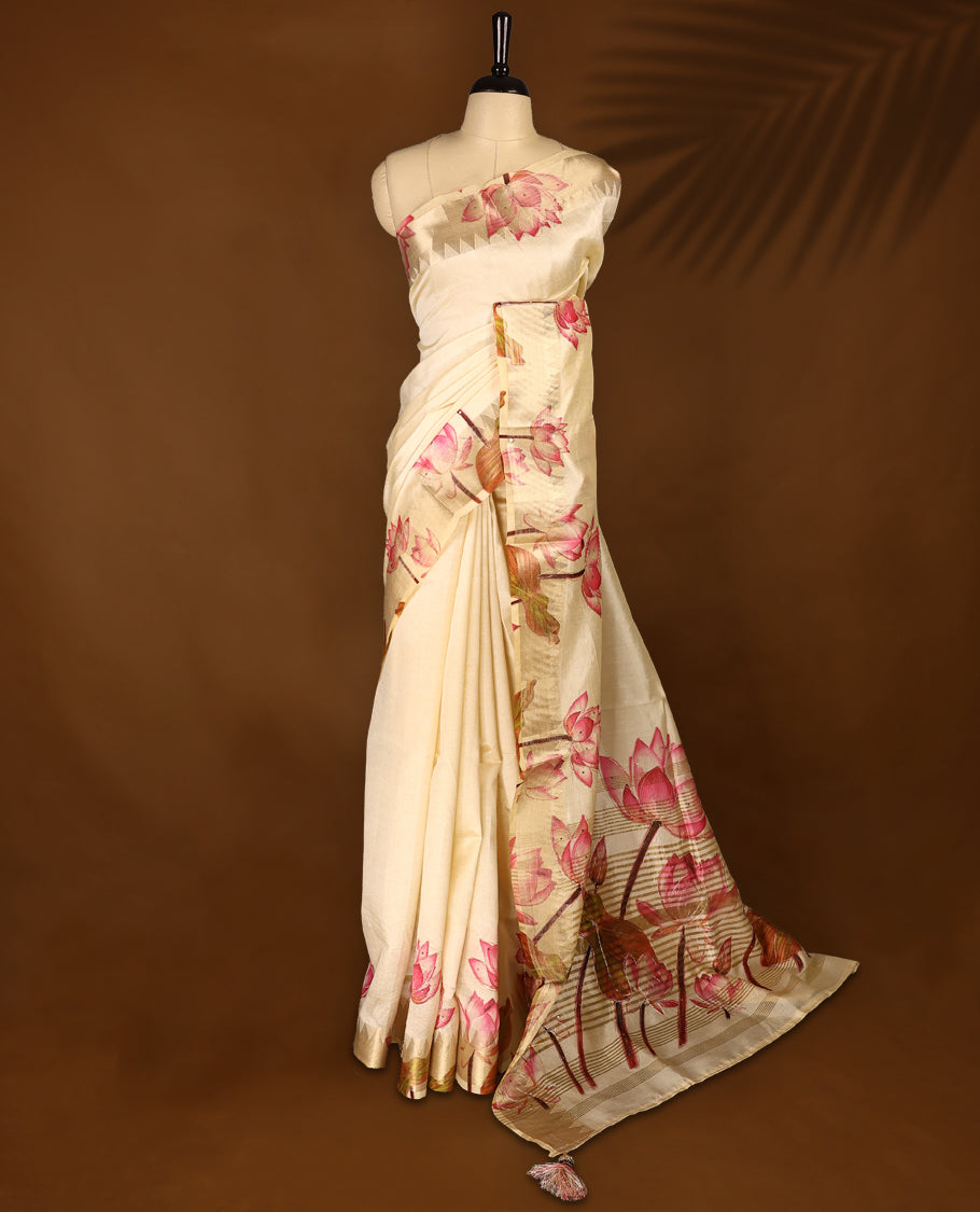 Off white colour Kerala saree crafted in soft tussar, adorned with vibrant pink lotus floral prints with thread and sequence work on the body and pallu, enhanced by a subtle golden zari border, Paired with a matching blouse.