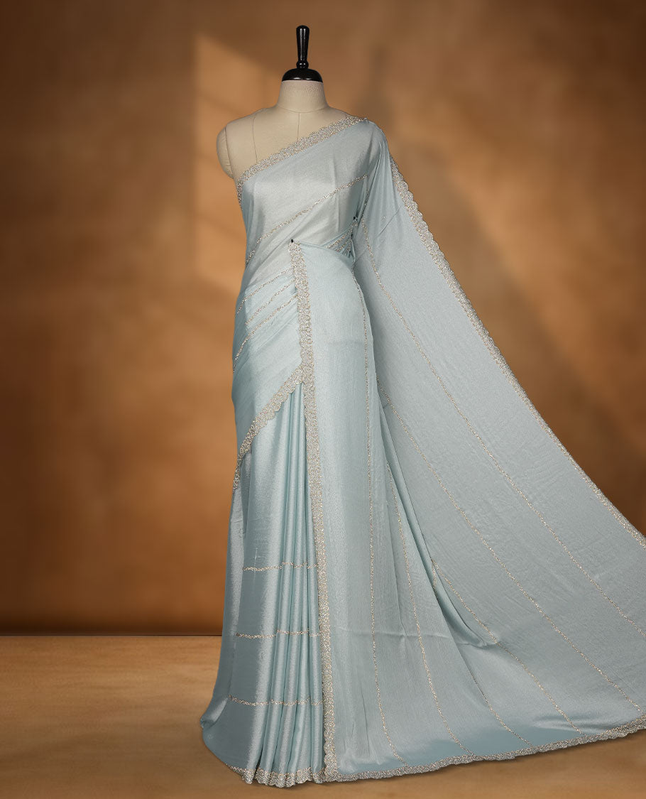Powder Blue colour net shimmer fancy saree with a plain body, paired with a delicate stone worked border, with matching blouse