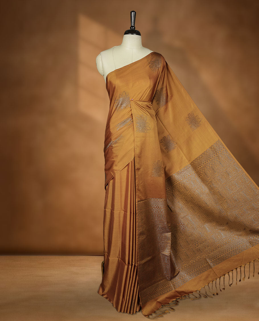 Dark Mustard colour semi soft silk saree adorned with delicate woven floral motifs on the body, complemented by a Self colour woven pallu with intricate detailing and tassel accents without border & Comes with a matching blouse piece.