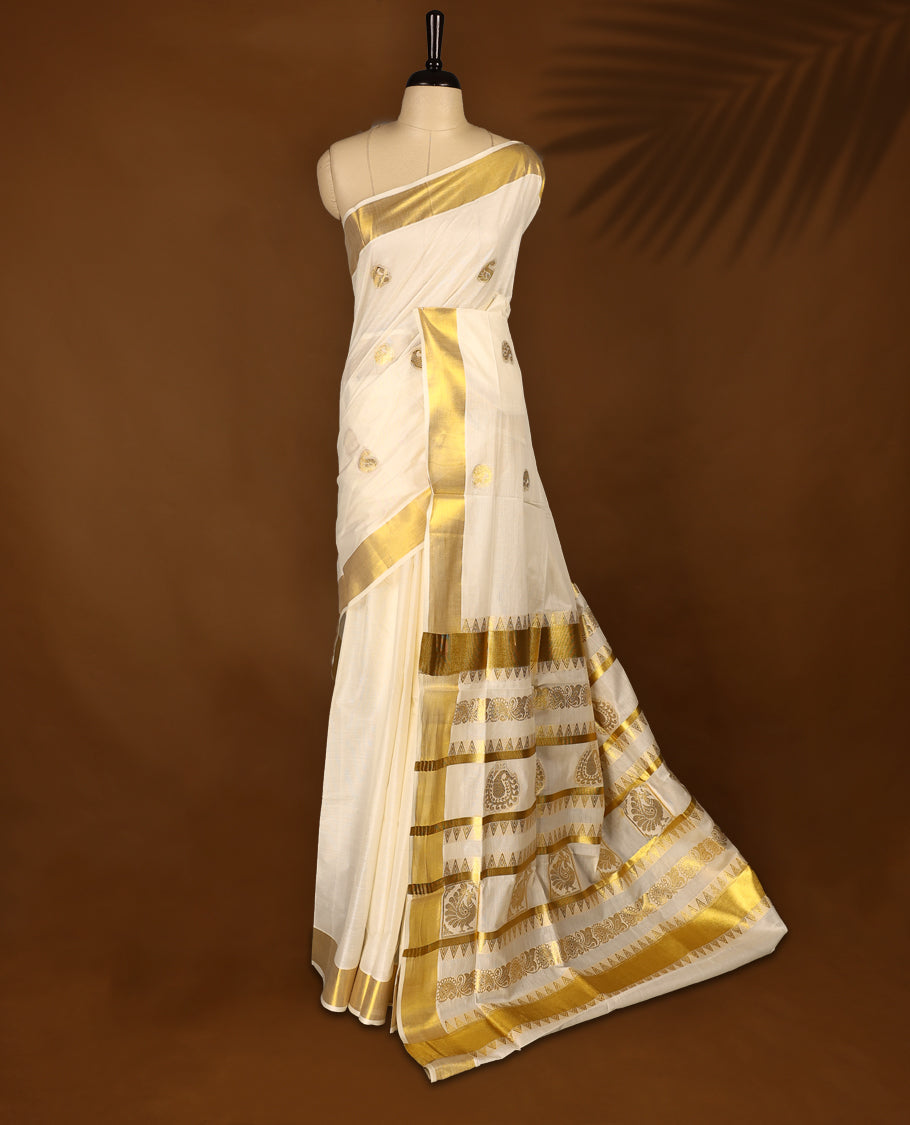 Elegant off white colour cotton Kerala saree featuring Gold zari motifs on body, traditional golden zari kasavu border & Rich Pallu offering a classic and graceful look, paired with a matching blouse.