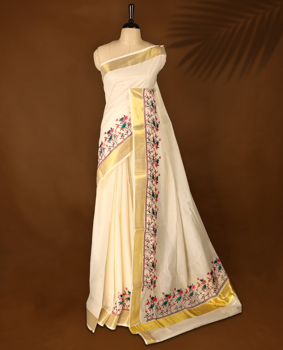 Light Gold colour Cotton Kerala saree featuring Plain body and a beautifully woven Gold Kasavu border with Heavy Green and Pink colour Floral embroidery work, paired with a matching blouse perfect for festive occasions.