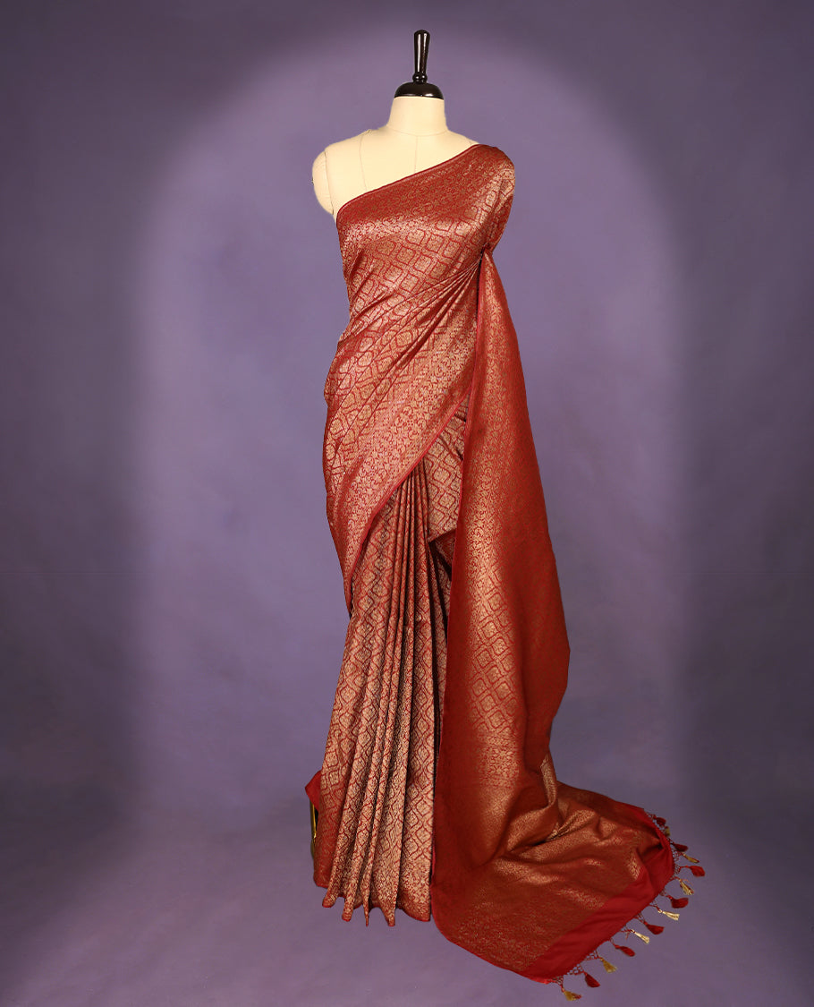 Maroon colour semi Banaras Katan saree featuring an antique Gold zari jacquard body, complemented by a self colour traditional border with a floral kodi design, paired with a matching blouse