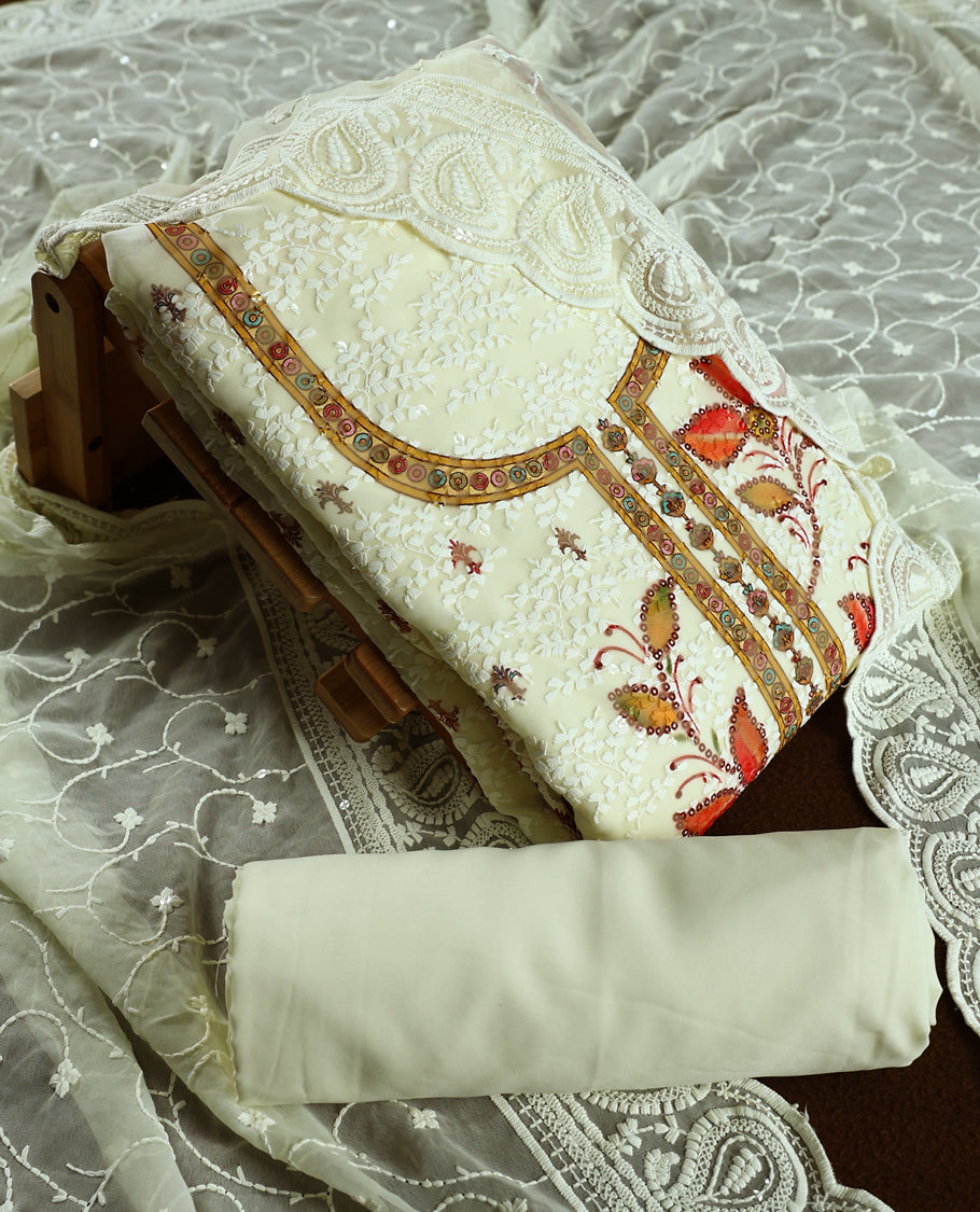 Cream colour churidhar material with embroidered yellow colour neck work, white thread floral motifs on the body, and multicolor floral detailing in yellow, orange, green & Comes with plain bottom and embroidered dupatta