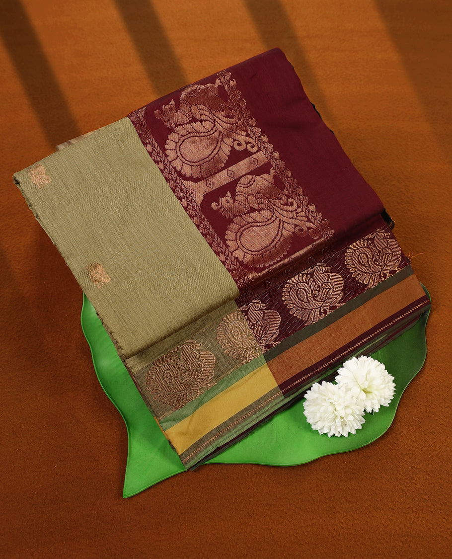 Olive Green and Maroon Kalyani cotton saree featuring subtle woven motifs on the body, accentuated with rich zari peacock designs on the border and pallu, paired with a matching blouse.