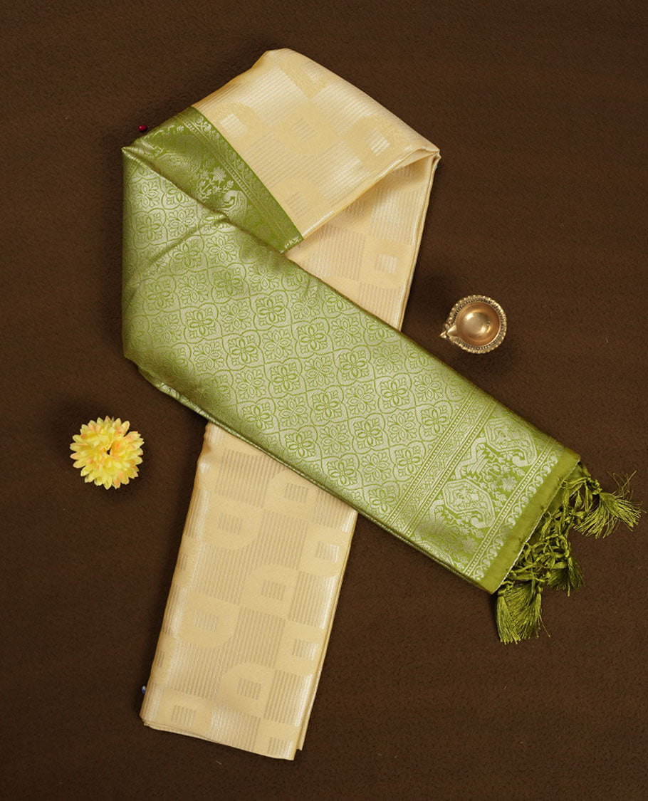 Light cream colour semi silk saree adorned with silver zari designs on the body, complemented by a contrasting olive green border and pallu, and paired with a matching blouse piece.