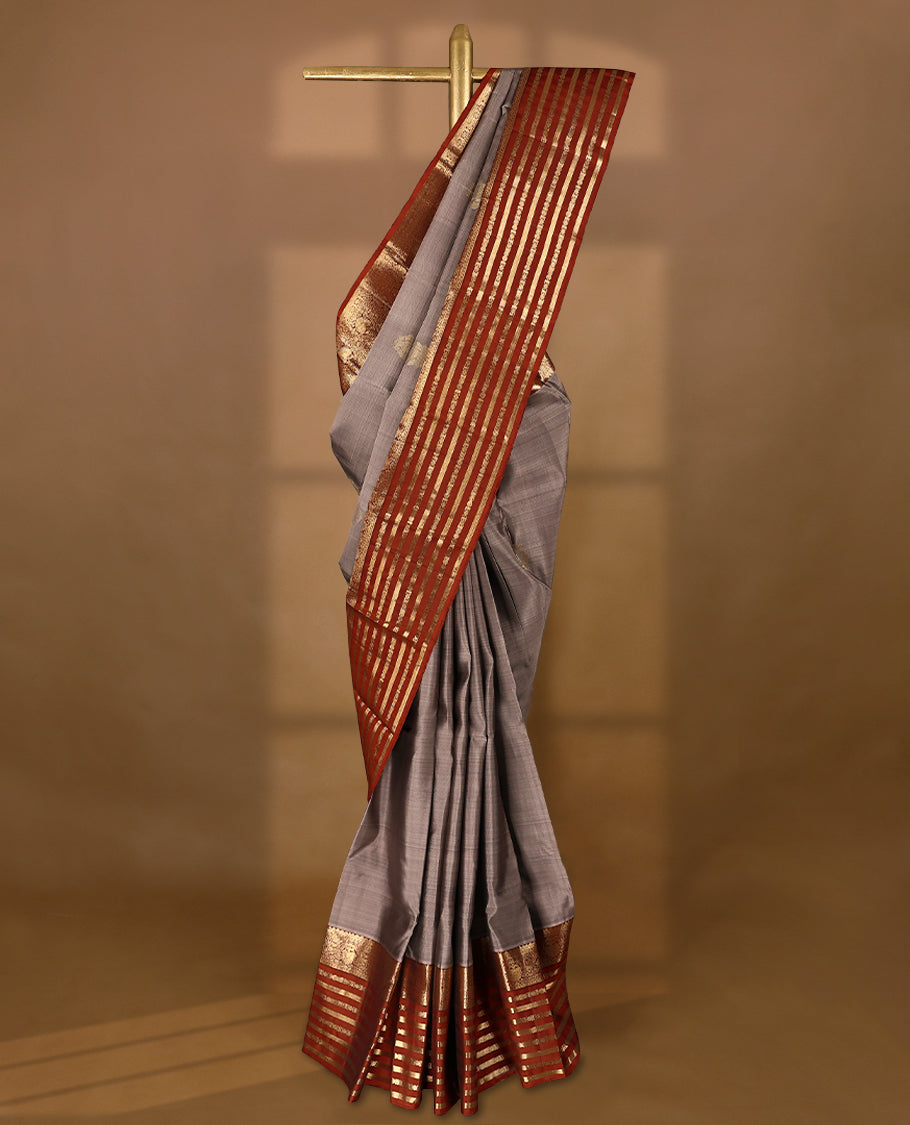 Muted lavender-grey Colour traditional Kancheepuram silk saree adorned with antique zari double peacock motifs on the body, rust red traditional border with alternating horizontal gold zari stripes and ornamental weaving , with a matching blouse.