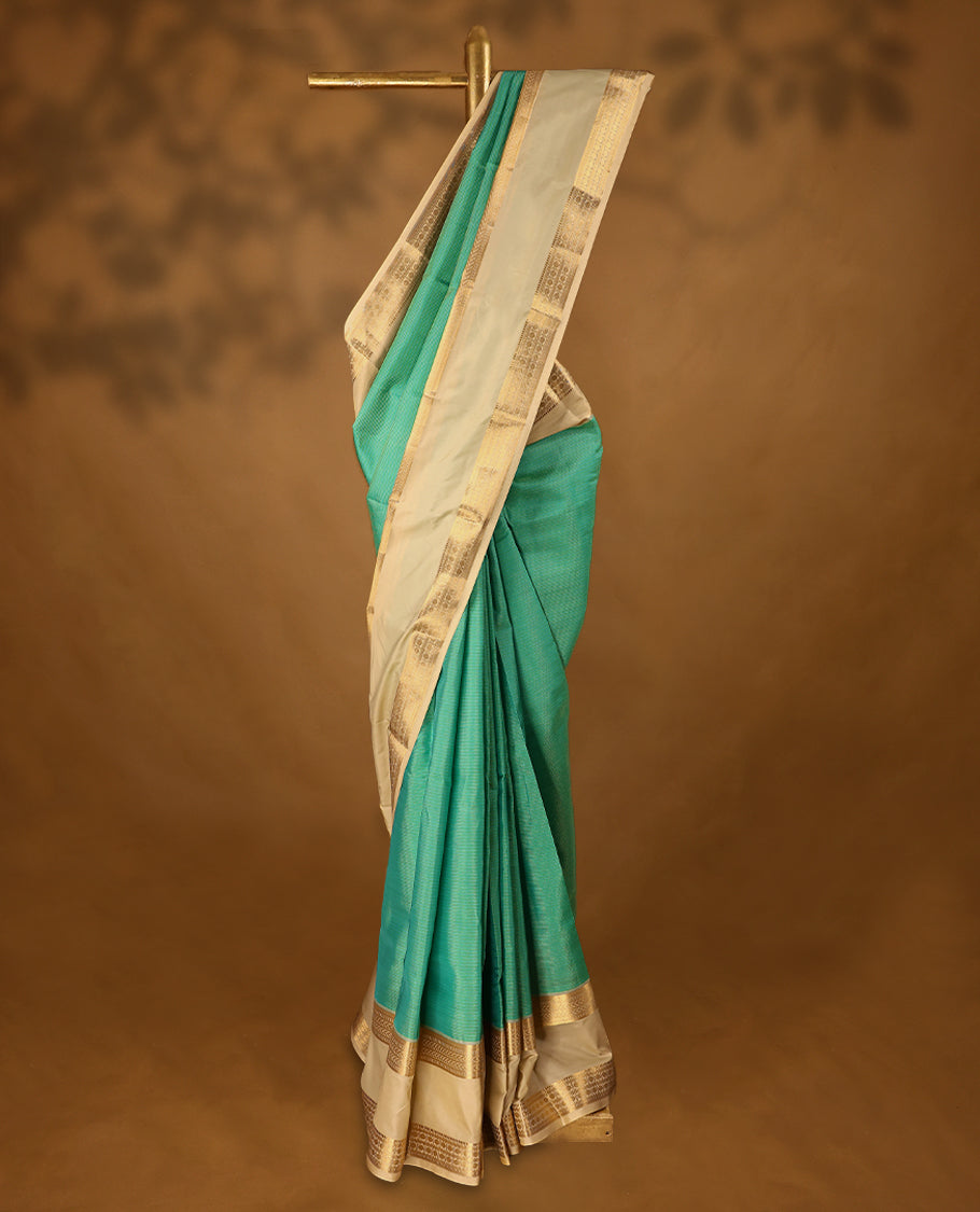 Aqua blue and green Colour soft silk saree adorned with golden zari stripes on the body, complemented by a contrasting traditional border, and paired with a matching contrast coloured blouse.