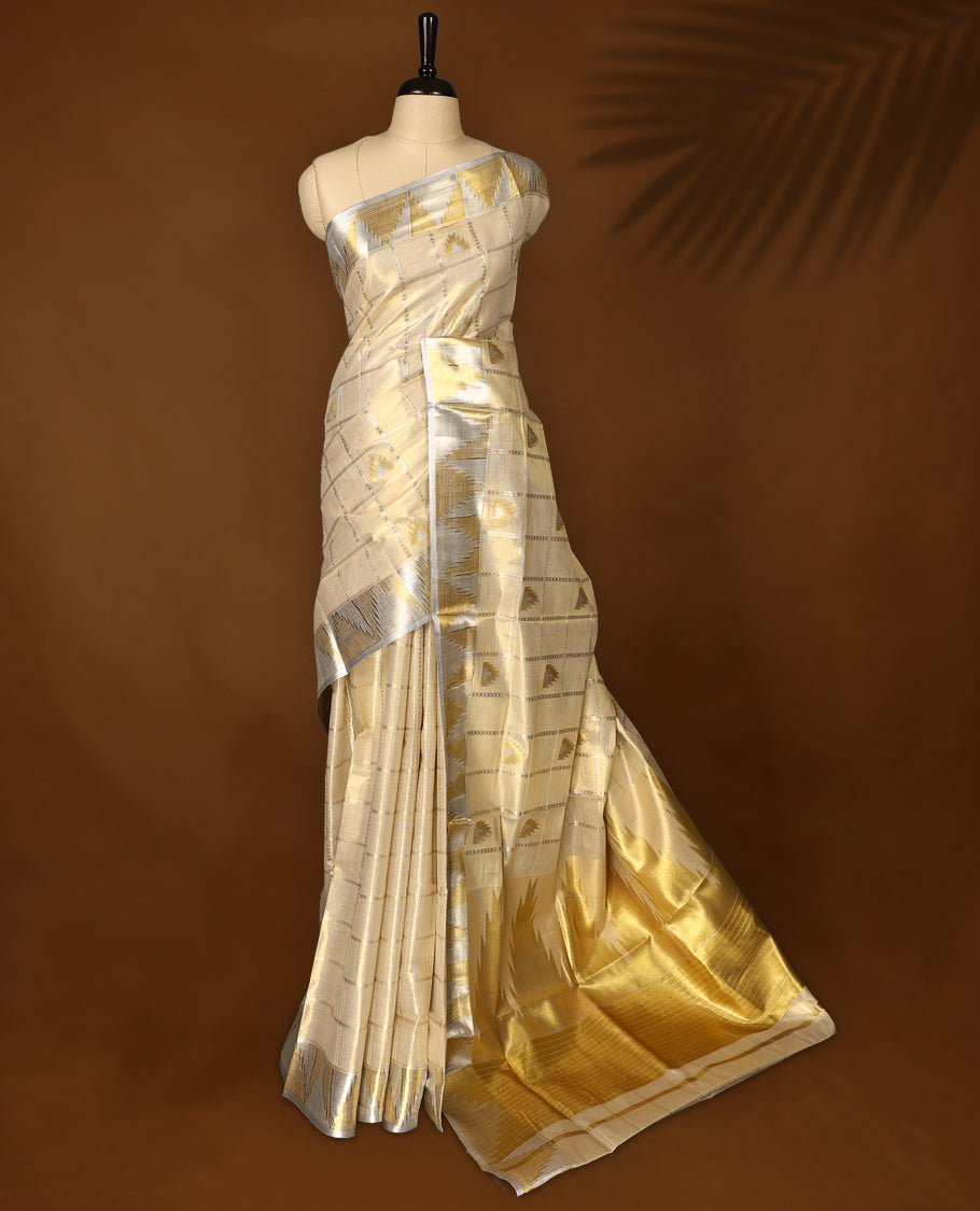 Elegant off white colour Tissue Kerala saree adorned with silver and gold geometric motifs on a checked body, enhanced by a shimmering silver kasavu border and rich golden pallu, paired with matching blouse for festive elegance.