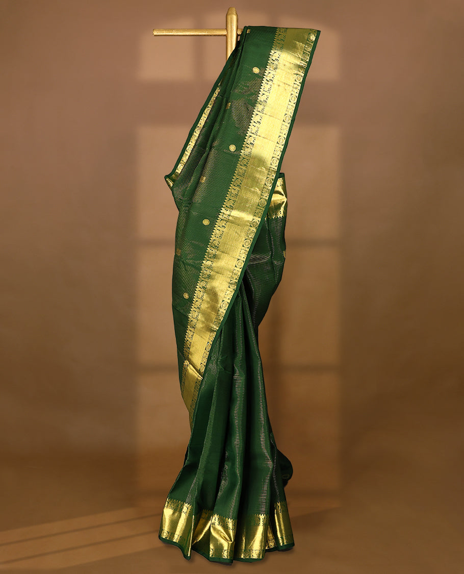 Bottle green Colour pure traditional Kancheepuramsilk saree featuring antique zari peacock and chakkram motifs on the body, complemented by a traditional border adorned with elephant and winged horse motifs, and paired with a matching Blouse
