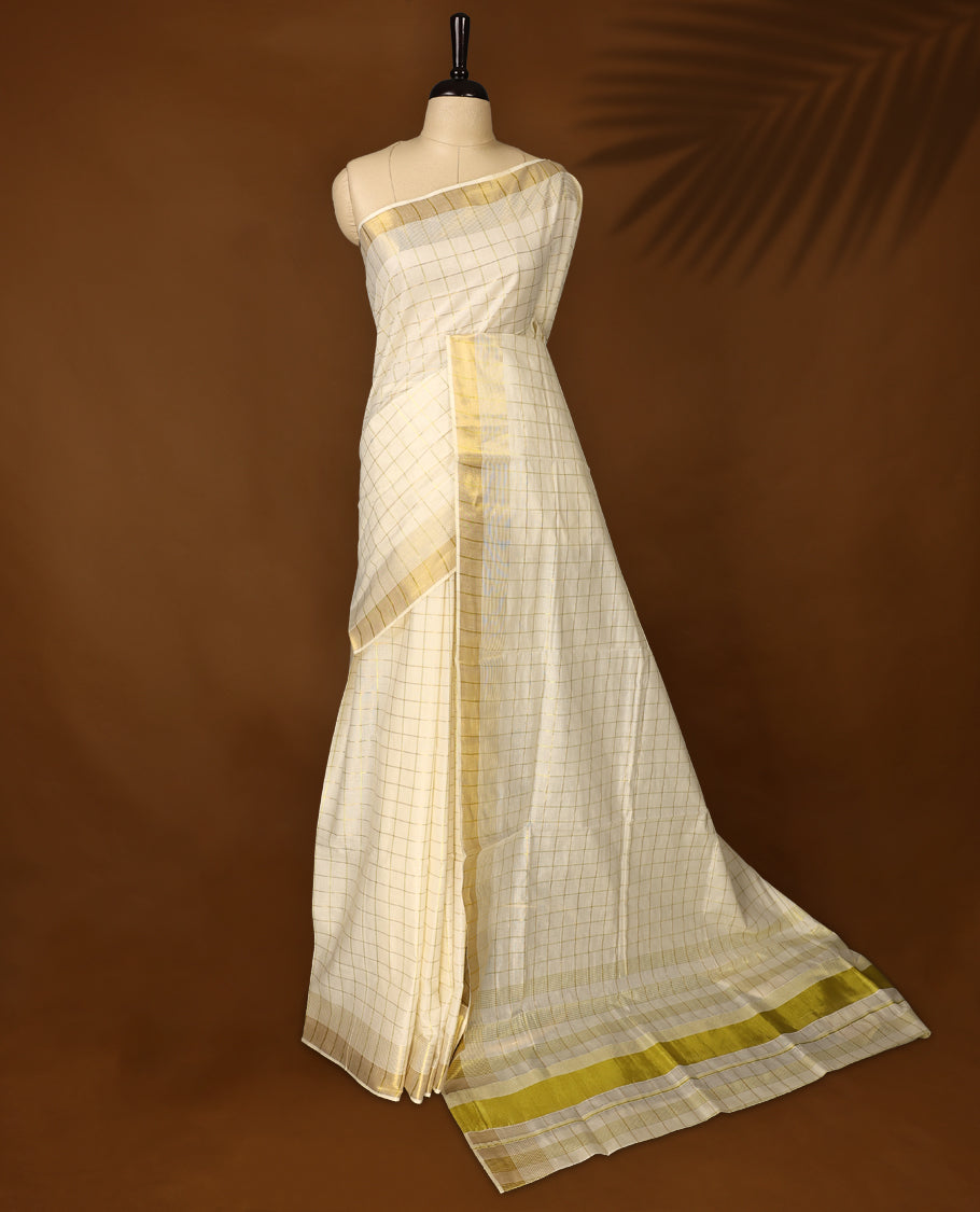 Elegant off white colour cotton Kerala saree with subtle golden and golden checked patterns and a broad golden zari border, Lightweight, breathable, and perfect for traditional events, Includes blouse piece.