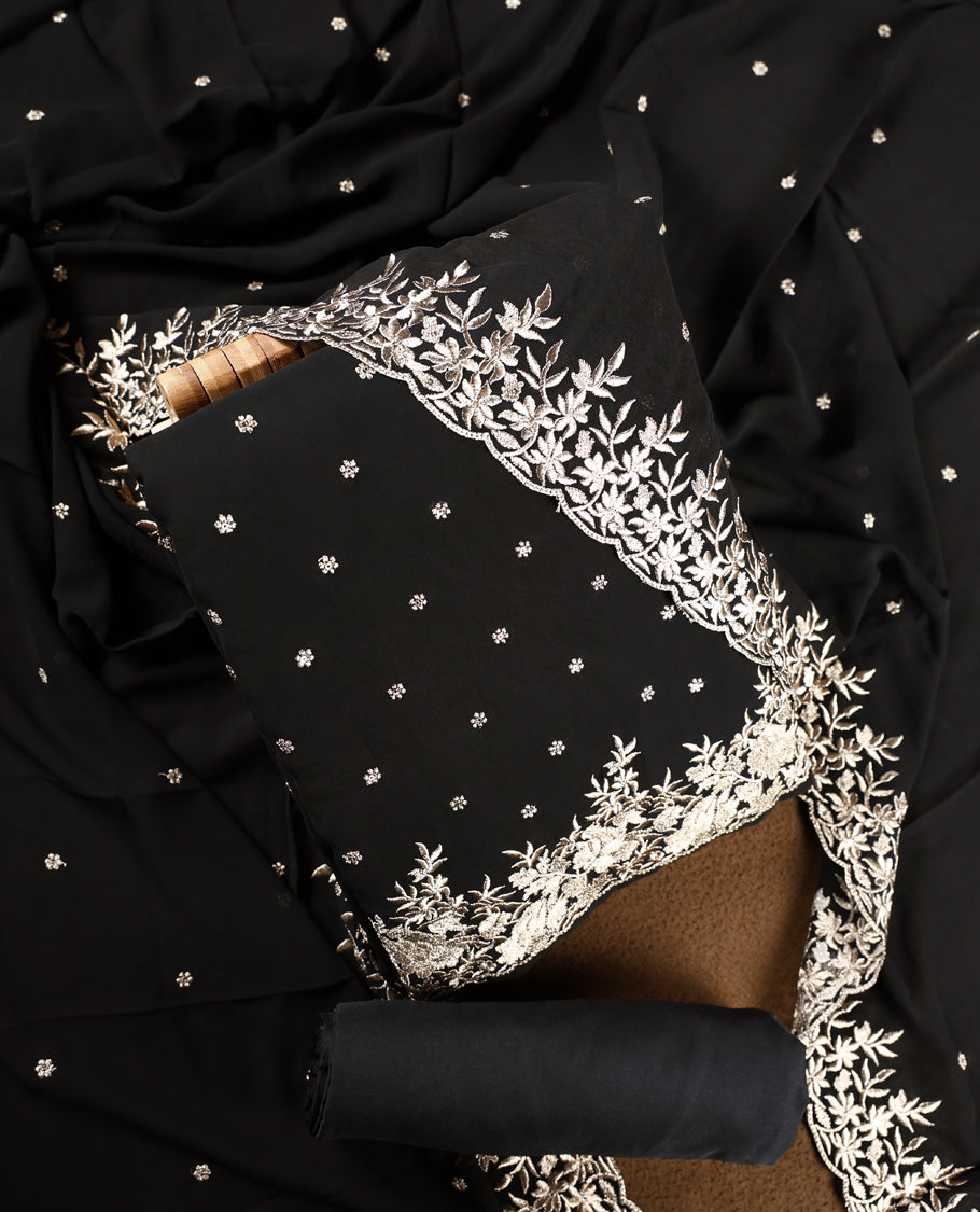 Black colour churidhar material beautifully designed with golden floral embroidery, thread highlights, paired with a plain matching bottom and an elegant embroidered dupatta.