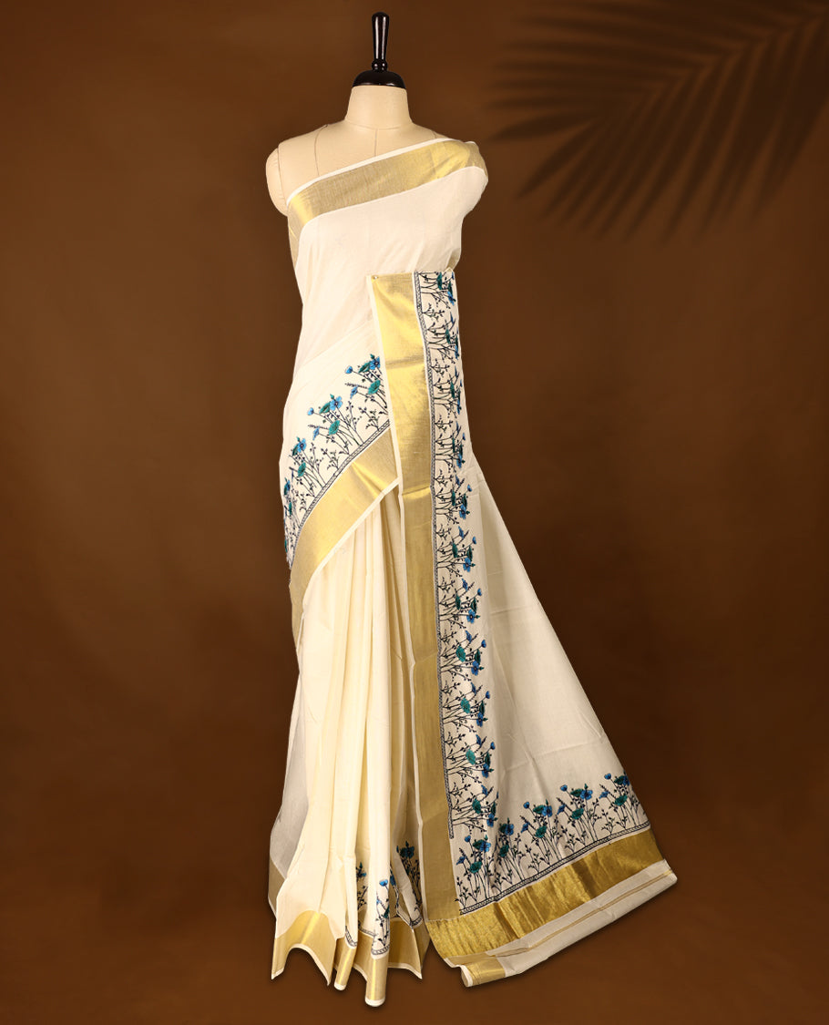 Light Gold colour Cotton Kerala saree featuring Plain body and a beautifully woven Gold Kasavu border with Heavy Blue and Green colour Floral embroidery work, paired with a matching blouse perfect for festive occasions.