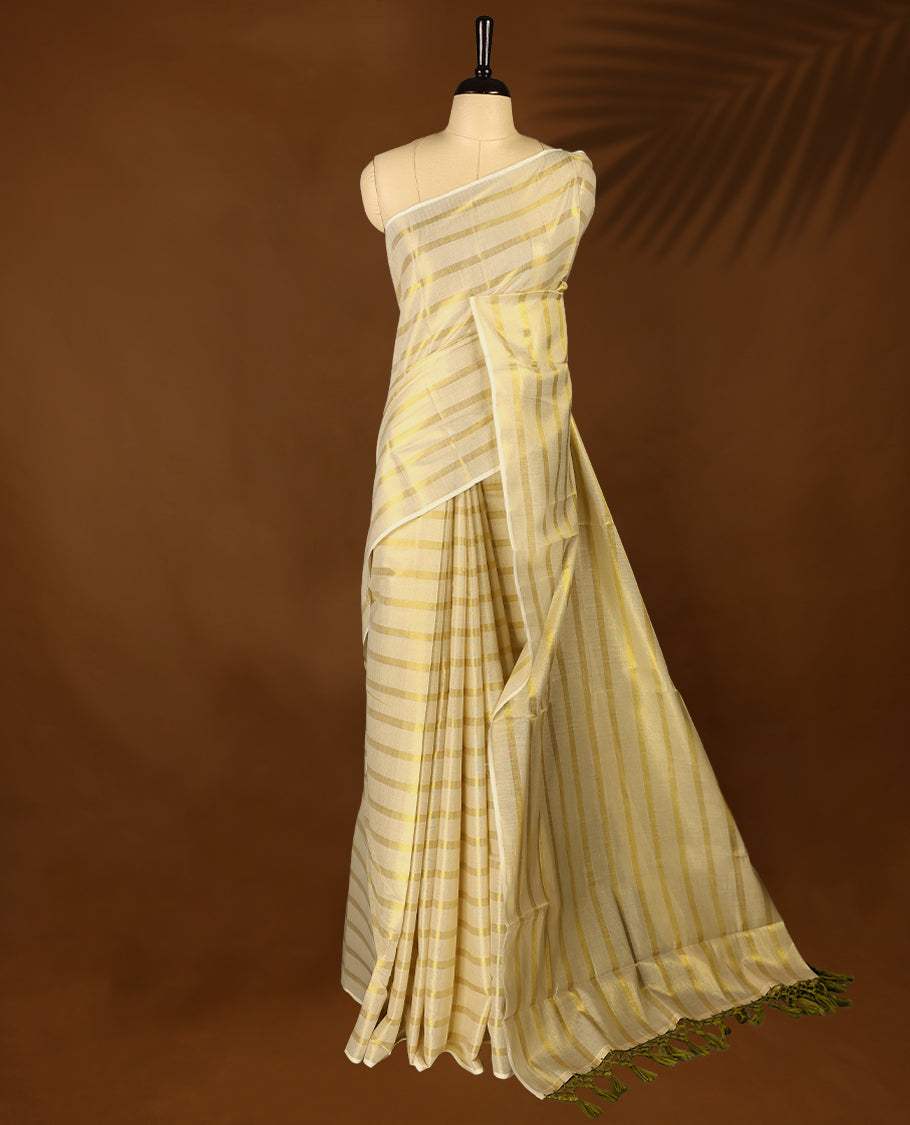 Light Gold colour Tissue Kerala saree featuring Gold zari Striped body, with Olive Green colour tassels with a matching blouse perfect for festive occasions.