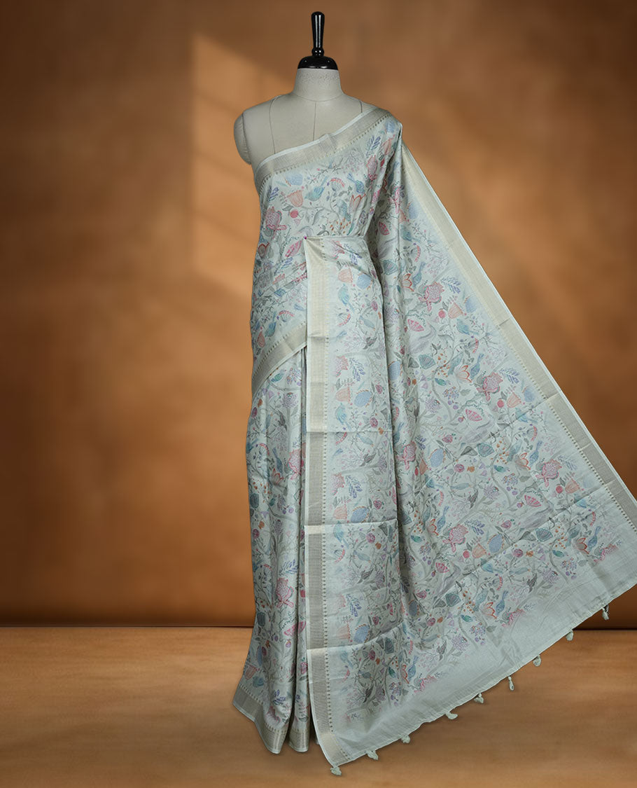Powder blue colour semi tussar silk saree featuring all over floral and leaf motifs on the body with a subtle self border and tasselled pallu, paired with a matching blouse.