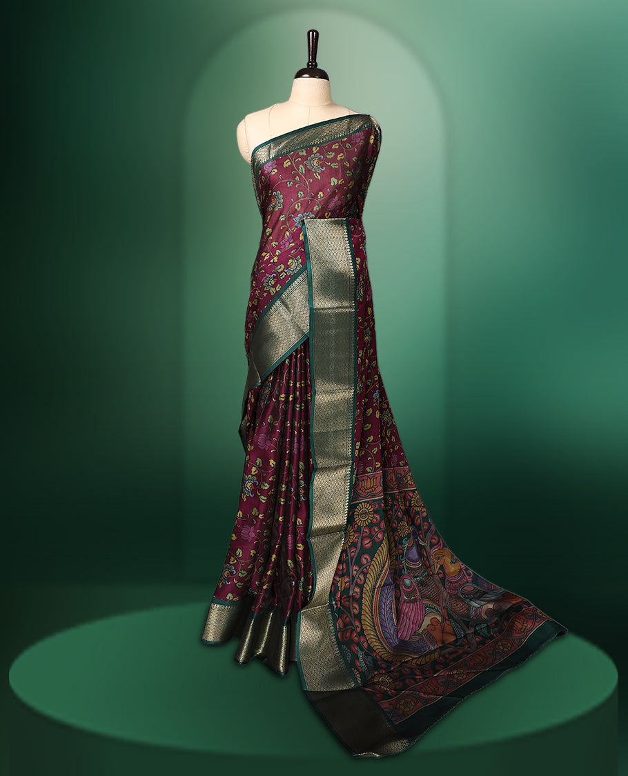 Rich Grape colour saree featuring intricate floral prints across the body, highlighted with a woven Green zari border, complemented by an artistic Kalamkari inspired pallu design, and paired with a matching blouse