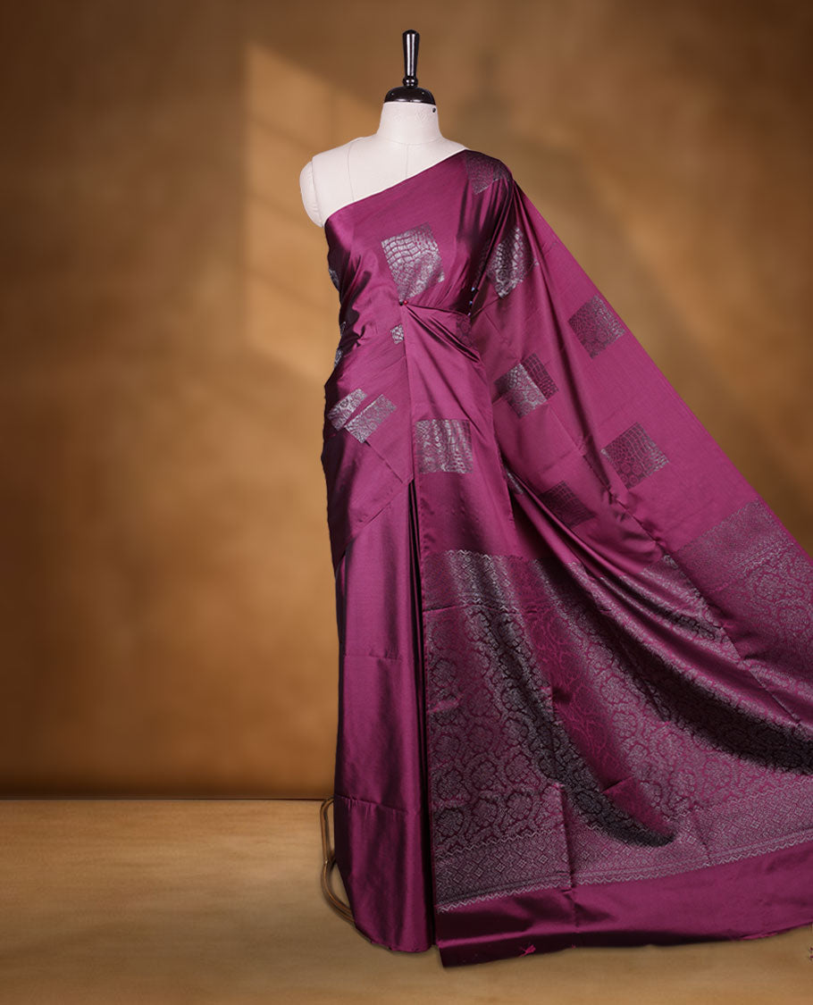 Deep purple colour semi soft silk saree adorned with delicate woven Square motifs on the body, complemented by a Self colour woven pallu with intricate detailing and tassel accents without border & Comes with a matching blouse piece.