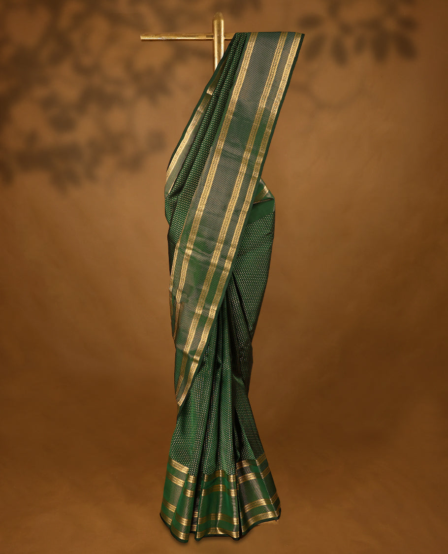Bottle green Colour soft silk saree adorned with delicate golden zari flower motifs, featuring a stunning Neli Kamalam design border complemented by a plain blouse in a matching self-tone colour