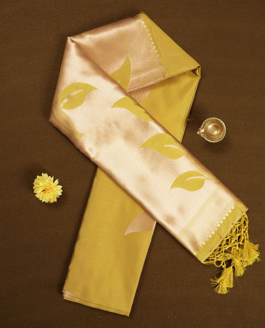 Mustard yellow colour semi silk saree adorned with elegant leaf motifs on the body, complemented by a shimmering golden zari woven pallu and border, and paired with a matching blouse