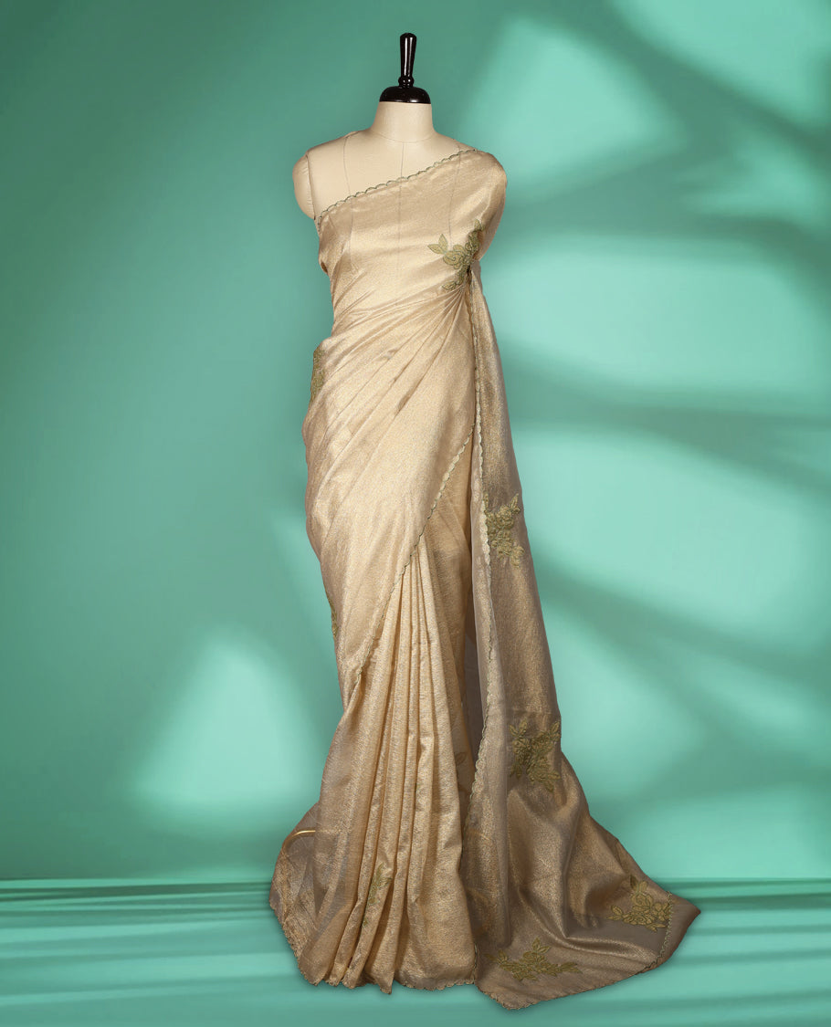 Beige gold colour organza designer saree featuring a subtle shimmer woven body with delicate green floral thread embroidery, scalloped thread detailing along the border and pallu paired with matching blouse.