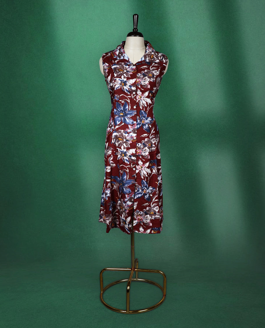 Maroon colour sleeveless dress featuring a collared neckline and button down front, adorned with bold blue and white floral prints a stylish and breathable choice for everyday elegance.