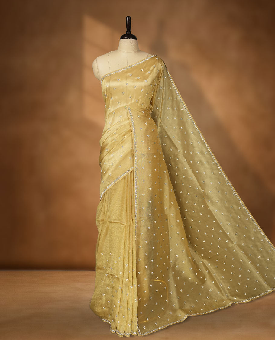 Golden Beige colour net shimmer fancy saree adorned with scattered white stone buttas all over the body, paired with a delicate stone worked border and matching blouse featuring floral vine stone embroidery