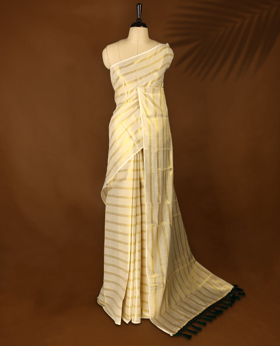 Light Gold colour Tissue Kerala saree featuring Gold zari Striped body, with Green colour tassels with a matching blouse perfect for festive occasions.