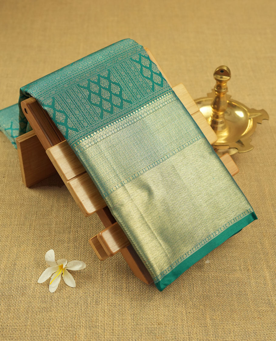 Turquoise blue colour Kanchipuram pattern Manthrakodi saree featuring golden zari box jacquard with small zari motifs across the body, traditional zari border, zigzag bavanji detailing, and plain zari blouse piece.