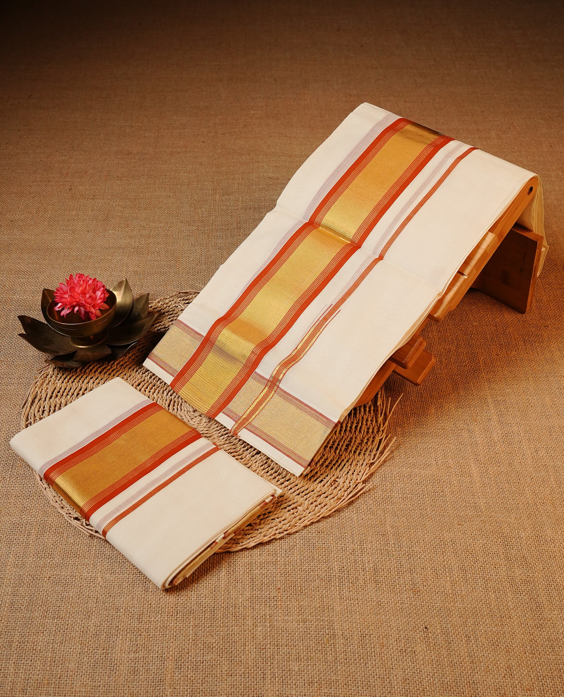 Off white colour Cotton Set Mund featuring a plain body, enhanced by a gold zari border with Brick red stripes.