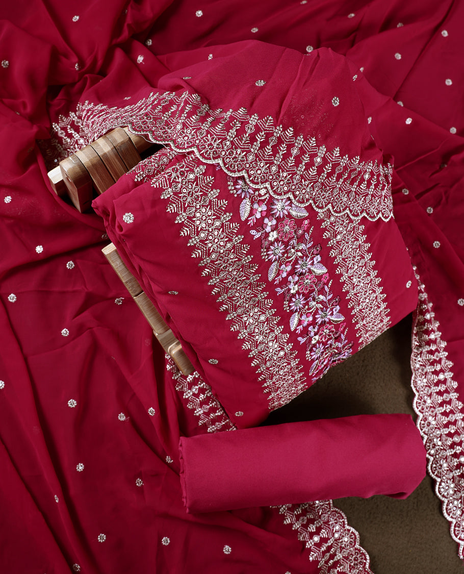 Pinkish red colour churidhar material beautifully designed with golden floral embroidery and multicolour thread highlights, paired with a plain matching bottom and an elegant embroidered dupatta.