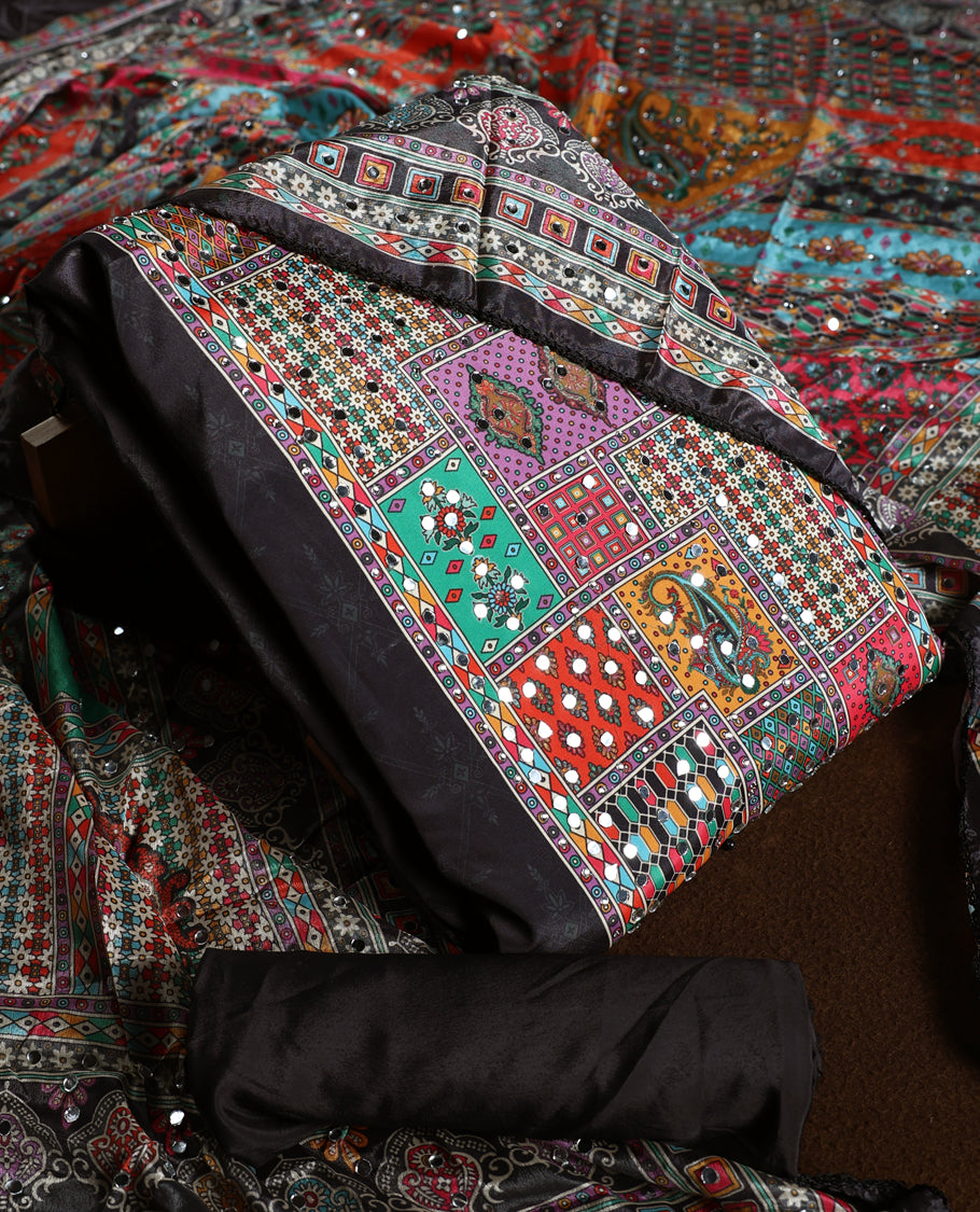 Striking black churidhar material featuring vibrant multicolour geometric and paisley prints highlighted with delicate mirror work, paired with a plain matching bottom and bold printed dupatta, ideal for festive occasions.