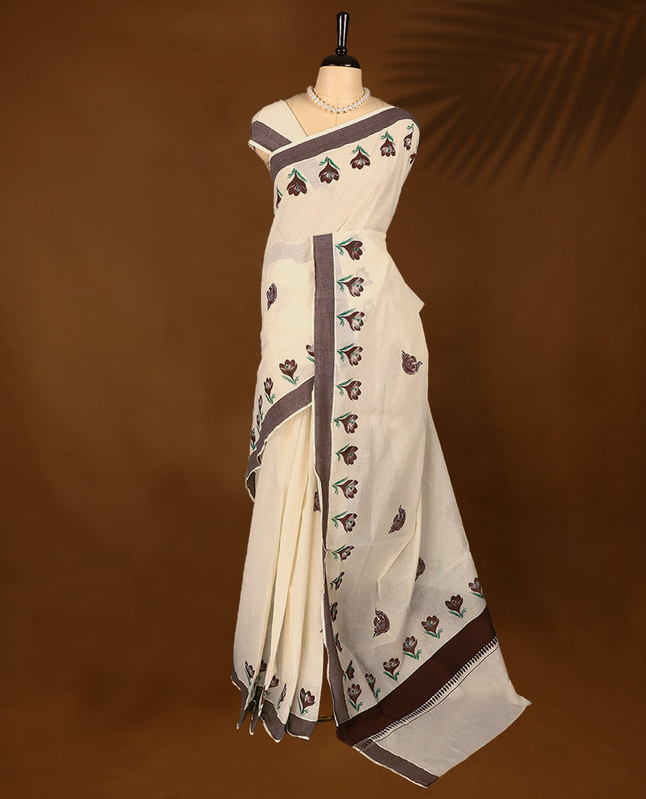 Kerala cotton saree features beautiful floral Prints in earthy tones, paired with a deep brown border with Matching Blouse.