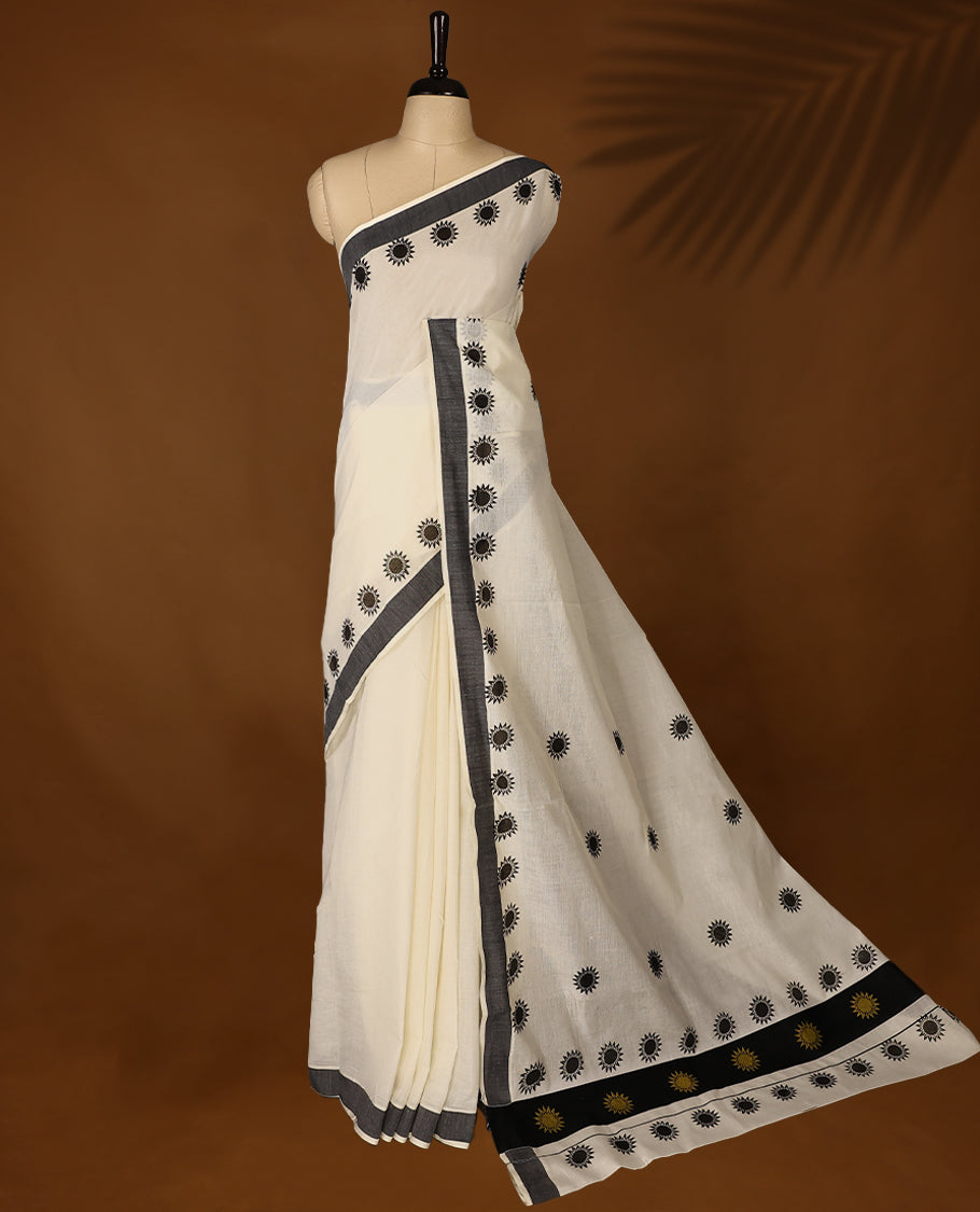 Elegant off white colour cotton Kerala saree featuring Plain body, Black colour border with Flower Block prints, Paired with matching blouse offering a classic and graceful look, paired with a matching blouse.