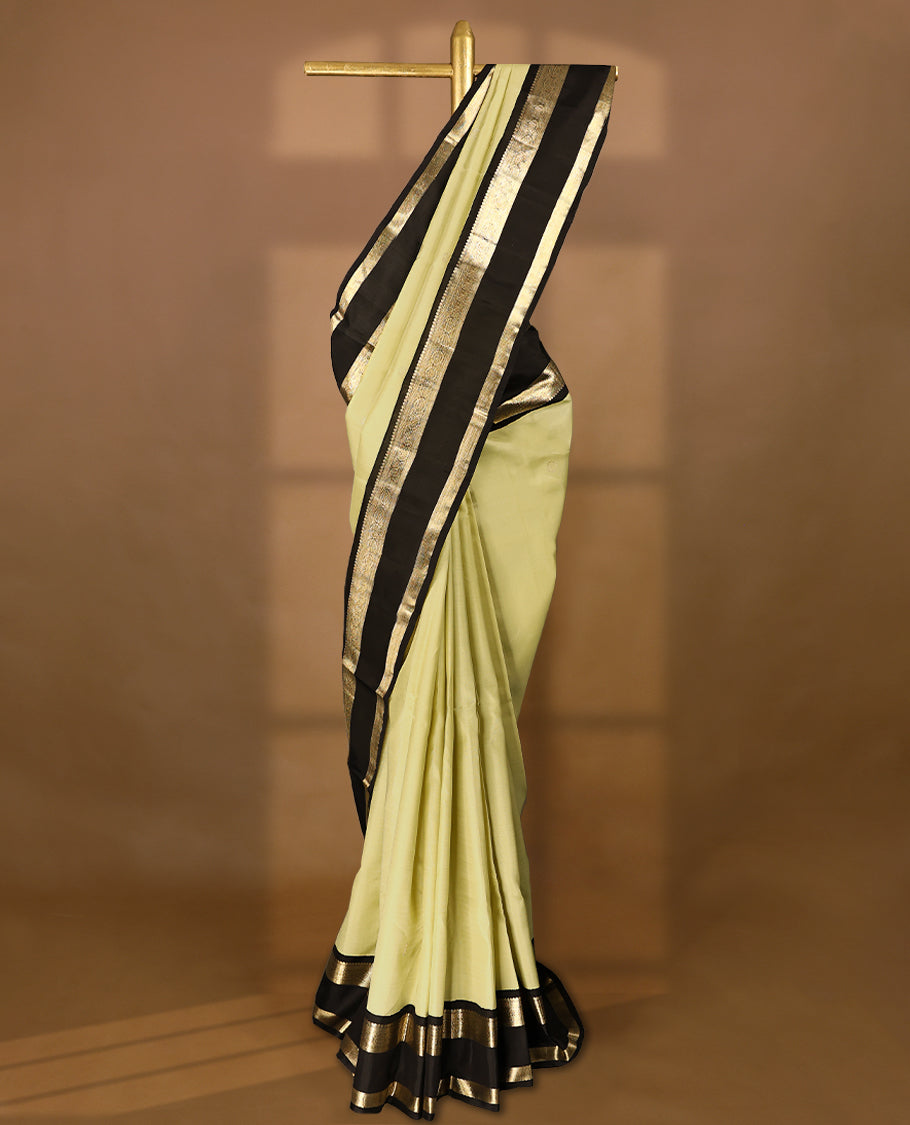 Key lime Colour pure traditional Kanchipuram silk saree adorned with intricately woven antique zari Chakkram motifs on the body, complemented by a Contrast black traditional border featuring Chakkram designs, and paired with a matching blouse.