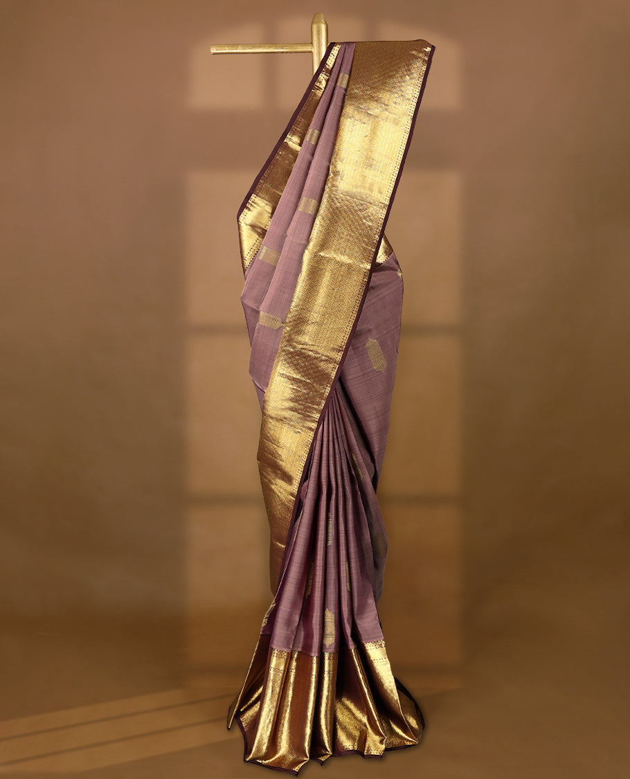 Muted mauve Colour traditional Kancheepuram silk saree adorned with antique zari traditional motifs on the body, featuring a contrasting border with Rich floral and geometric patterns, and paired with a matching blouse.