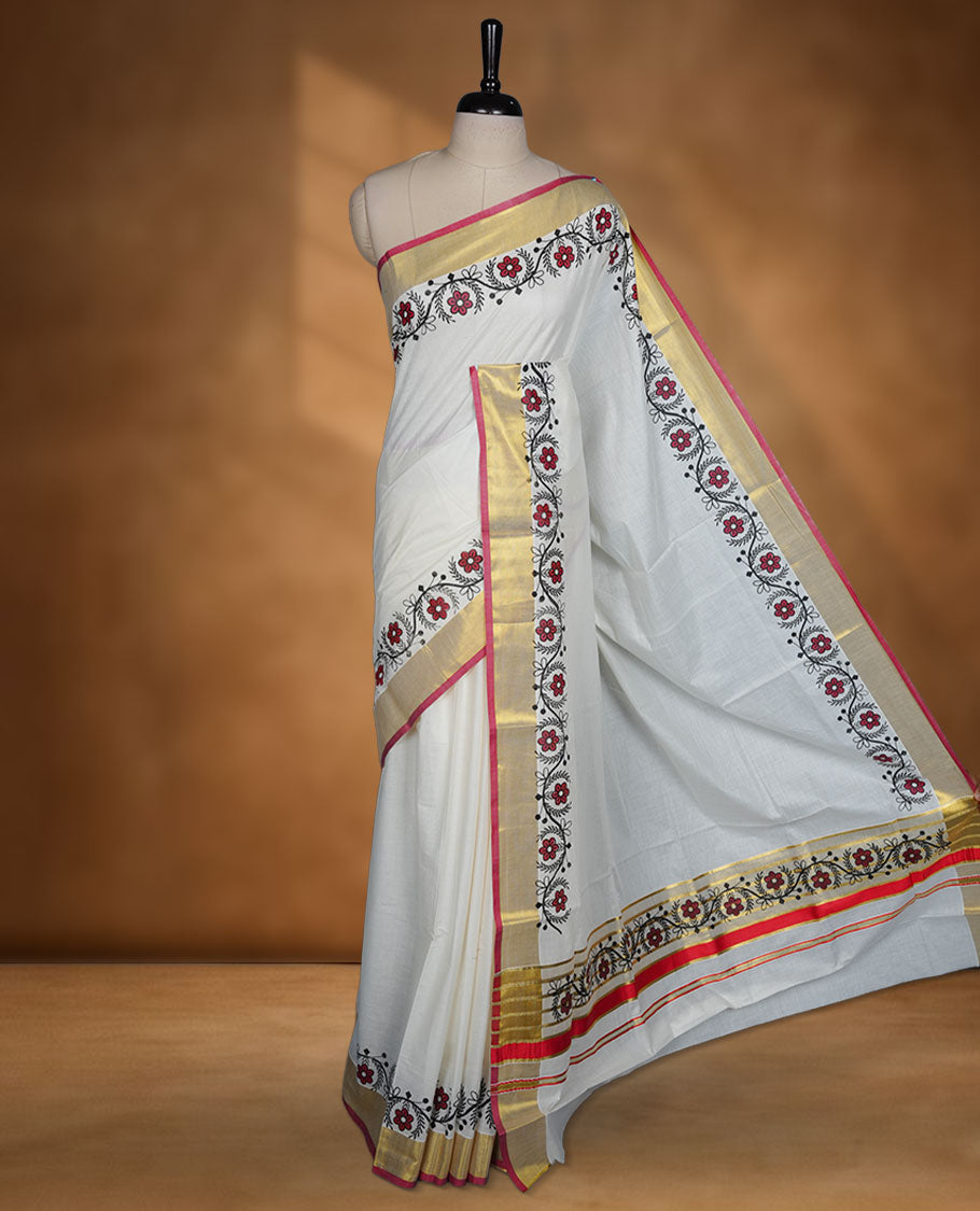 Off white cotton Kerala saree with floral printed borders, highlighted by a golden zari border and classic pallu, paired with a matching blouse.