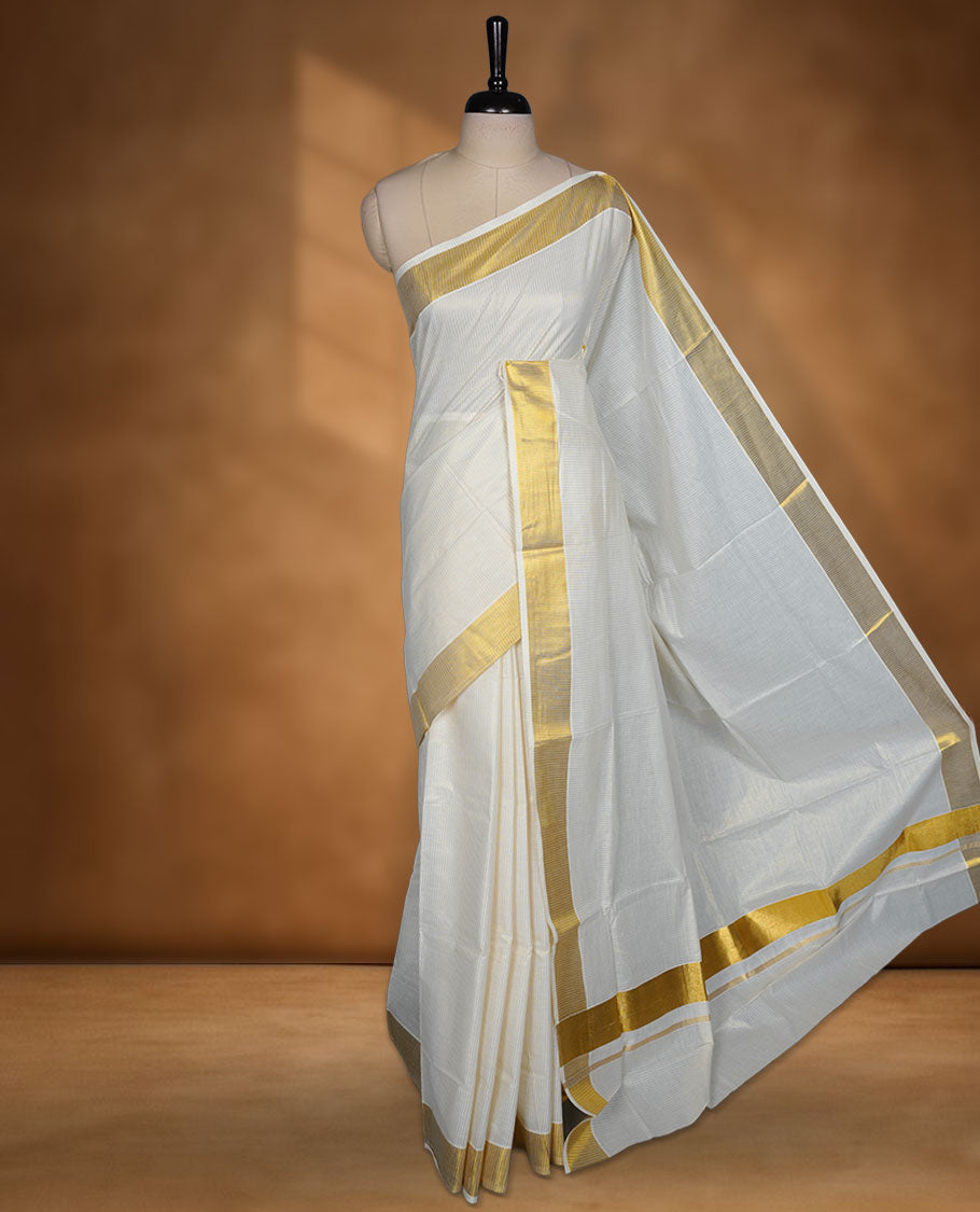 Off white colour Kerala cotton saree featuring fine golden stripes, complemented by a classic zari border and traditional pallu, paired with a matching blouse.