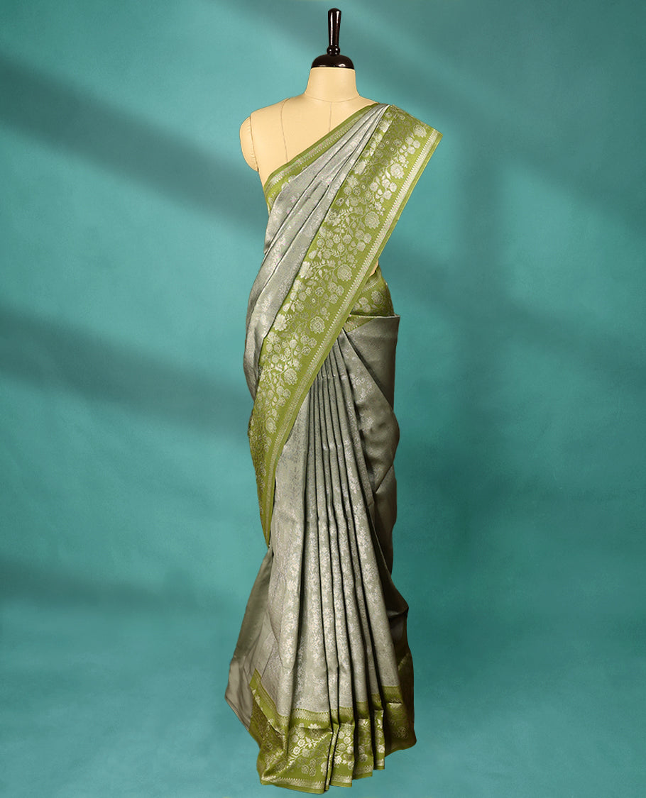 Light Pista coloured semi silk saree featuring a Silver coloured floral jaal design on the body, paired with a Green coloured border and matching blouse.