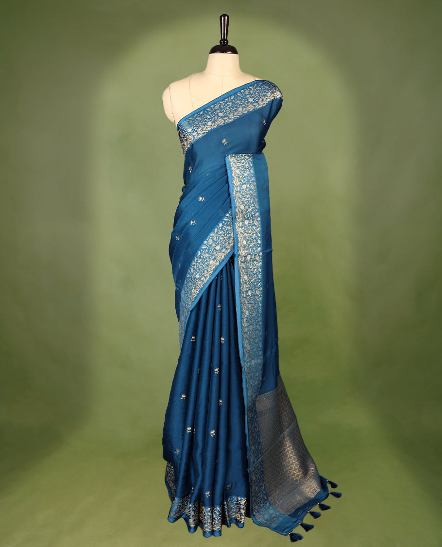 Peacock Blue colour pure Banaras crepe saree showcases elegant Gold zari Flower Motifs all over the body, a traditional gold & Silver zari border, a rich intricately woven pallu, and comes with a matching blouse.