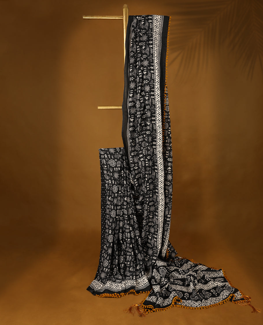 Black cotton saree features intricate white handblock prints, a beautifully detailed border with mustard piping and Self Coloured Blouse