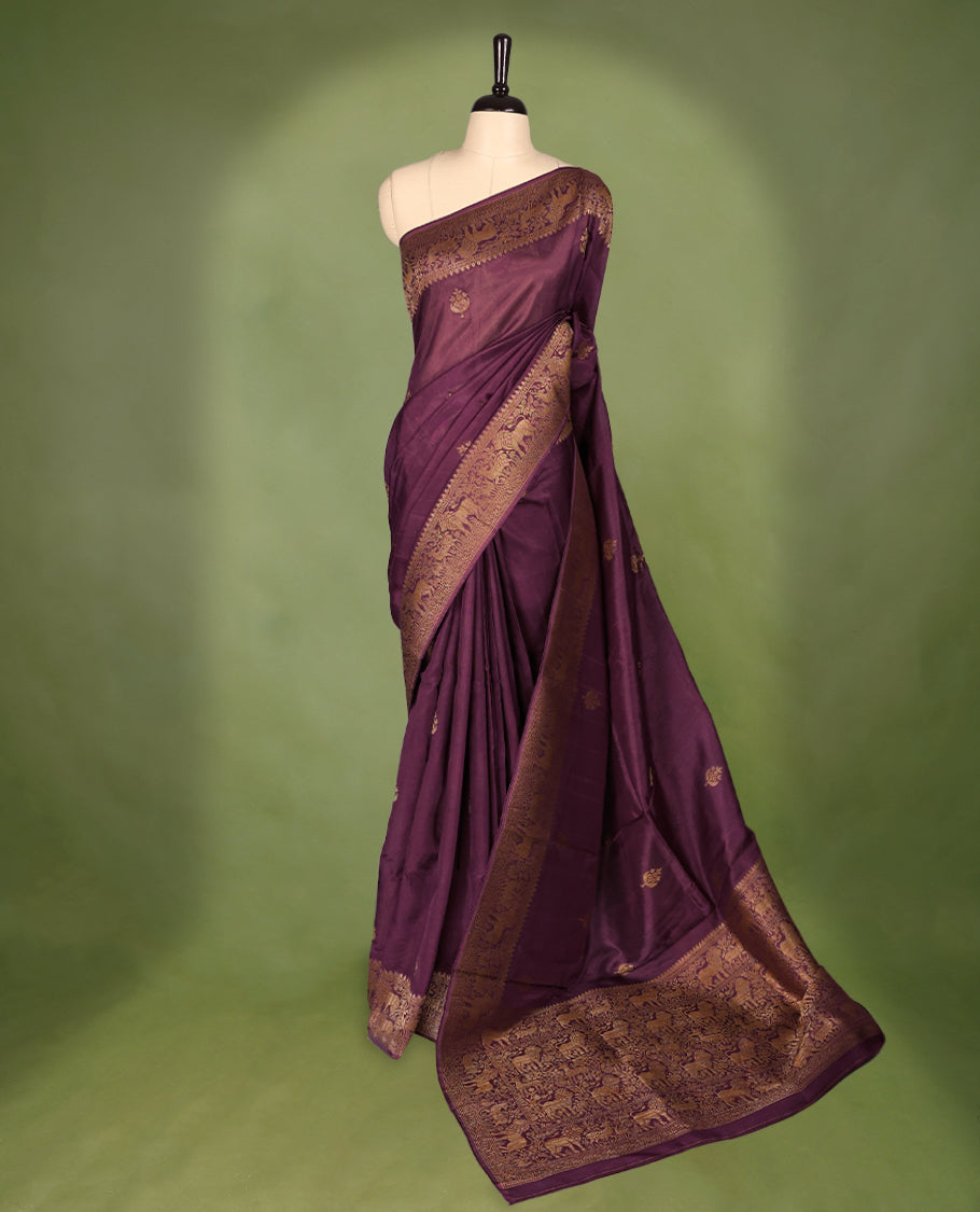 Light black currant semi Banaras tussar georgette saree adorned with antique zari butta motifs on the body, accentuated by a beautifully crafted jungle themed border, and paired with a matching blouse.