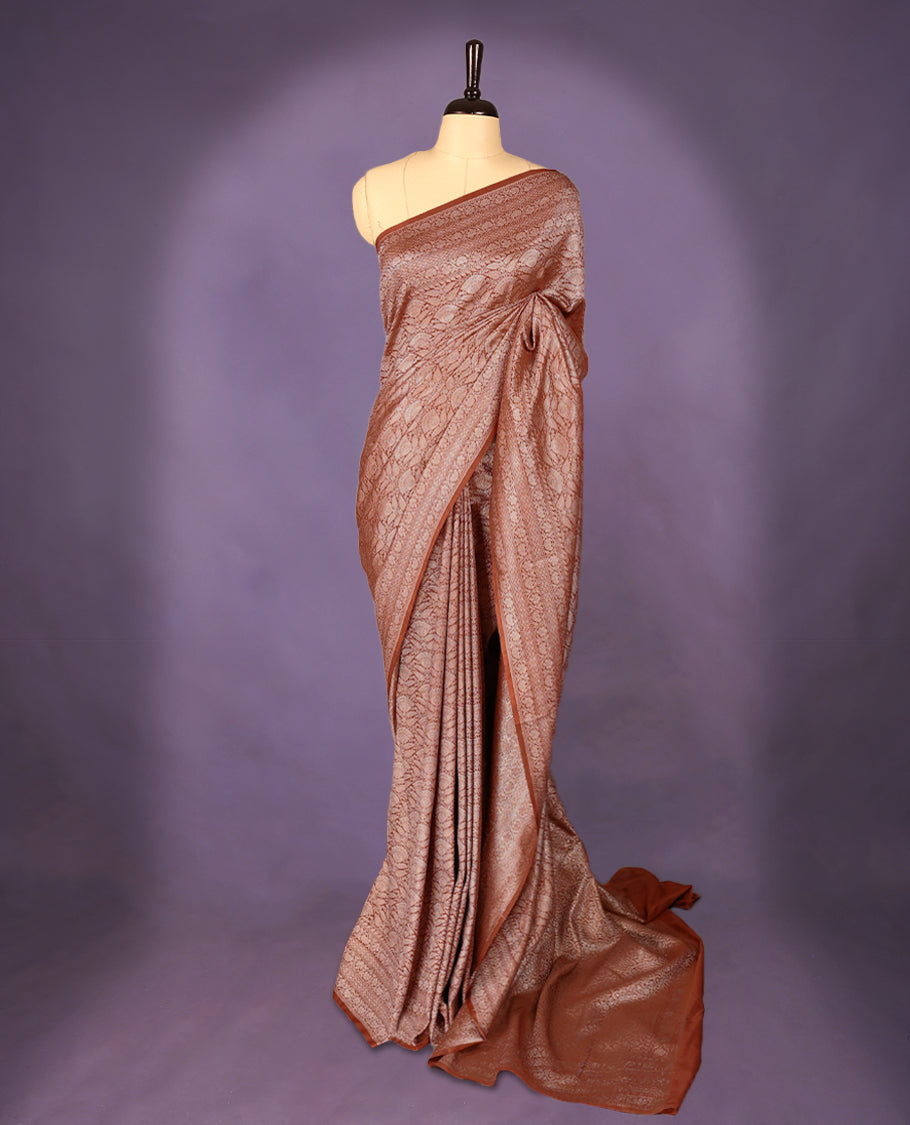 Light brown colour semi Banaras Katan saree featuring an antique silver zari jacquard body, complemented by a self colour traditional border with a floral kodi design, paired with a matching blouse