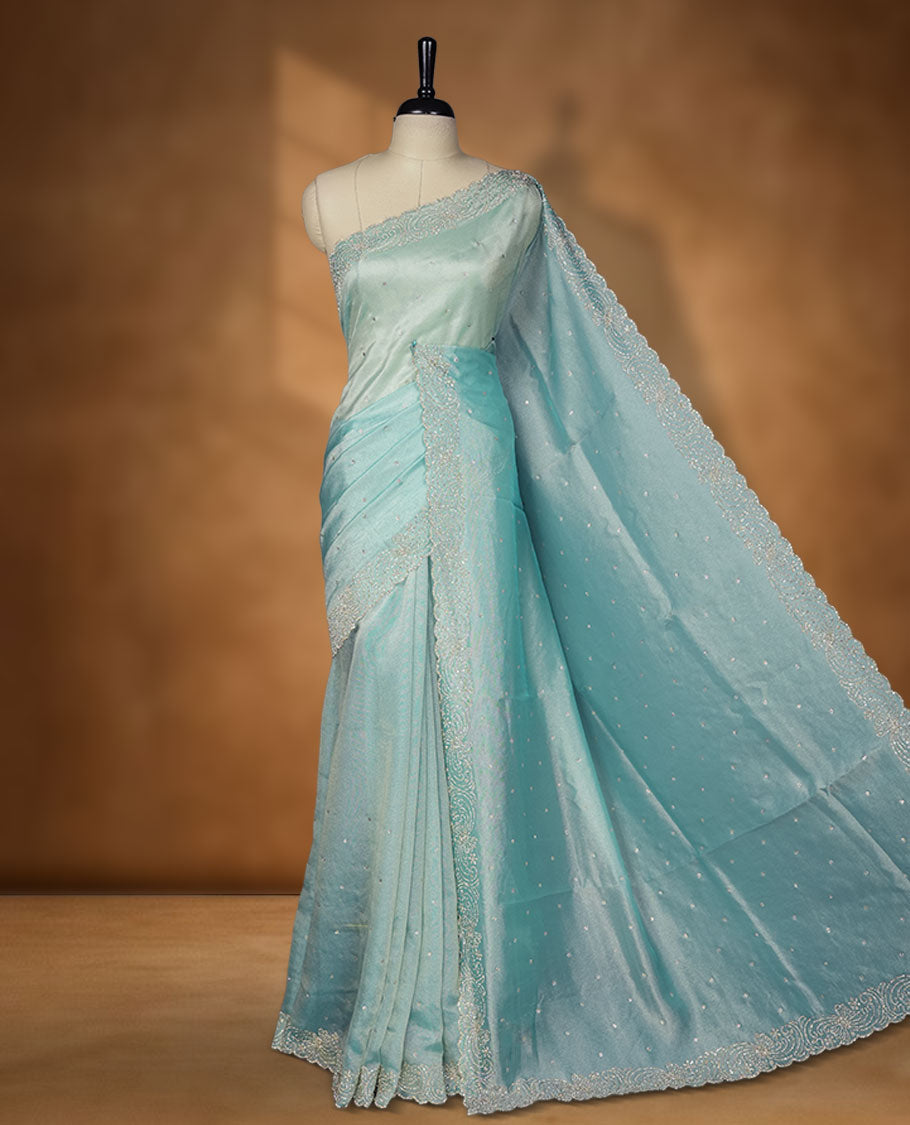 Pastel aqua blue Colour net shimmer fancy saree adorned with scattered white stone buttas all over the body, paired with a delicate stone worked border and matching blouse featuring floral vine stone embroidery.