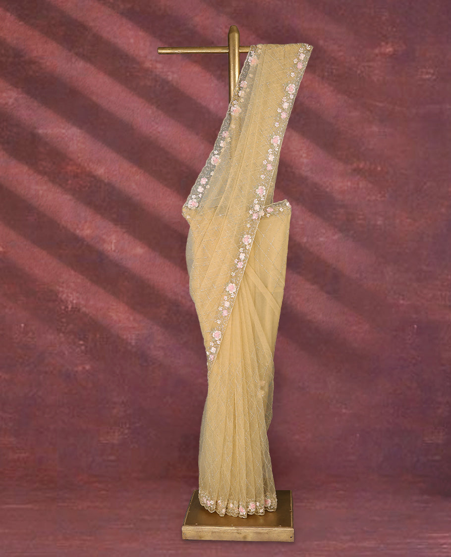 Pastel yellow colour net designer saree featuring crisscross cut beads detailing on the body, adorned with beads and sequin worked floral kodi scallop border, paired with a matching worked blouse