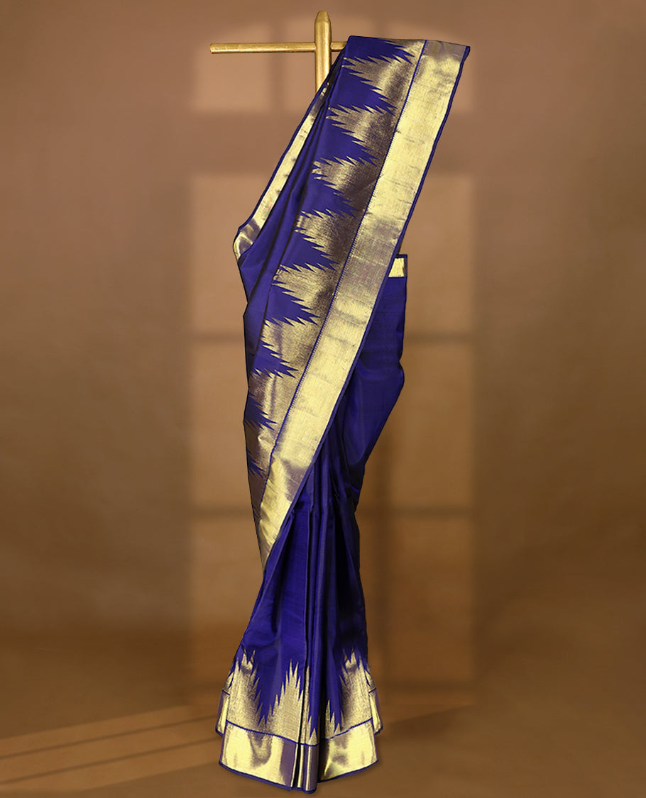 Navy blue pure traditional Kancheepuram silk saree featuring a plain body, complemented by a traditional border adorned with temple motifs, and paired with a matching blouse.