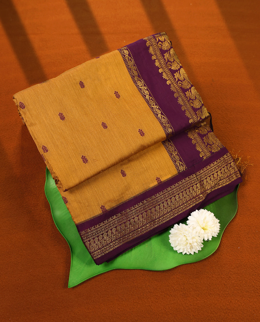 Mustard Yellow colour Kalyani cotton saree featuring woven maroon butta motifs throughout the body, paired with a rich Purple colour traditional zari woven border and pallu, with matching blouse.