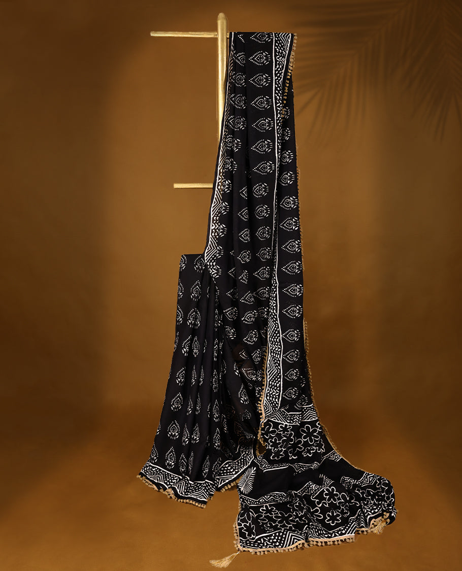 Black cotton saree features intricate white handblock prints, a beautifully detailed border with Beige piping and Self Coloured Blouse